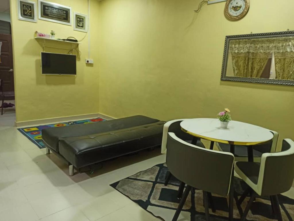 een woonkamer met een bank en een tafel en stoelen bij Homestay FarHaA in Tanah Merah
