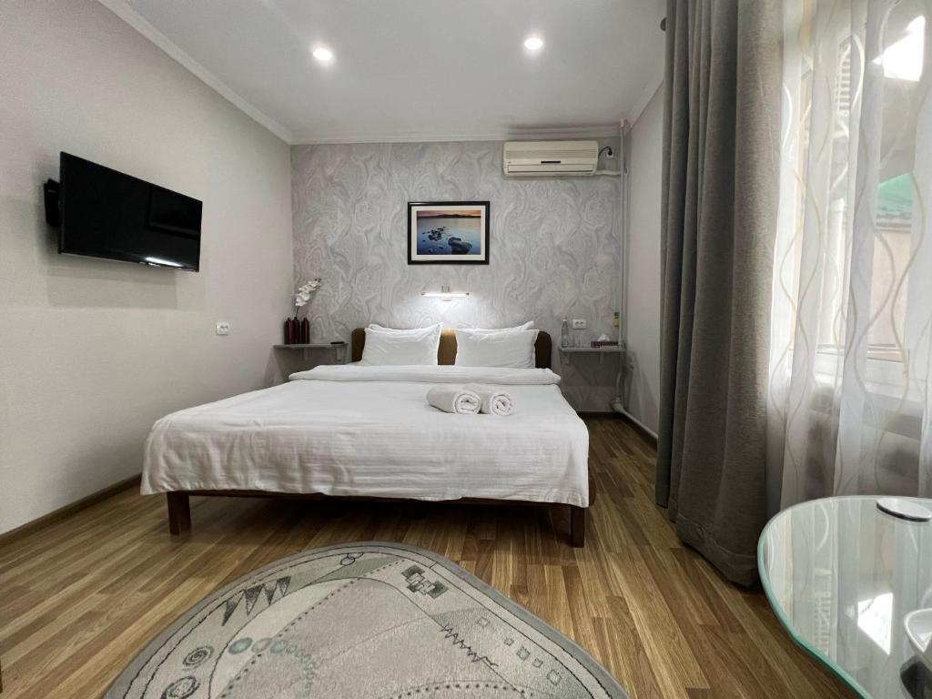 塔什坎的住宿－FRОDО - Cozy as a home for 2-5 persons，卧室配有一张白色大床和电视。
