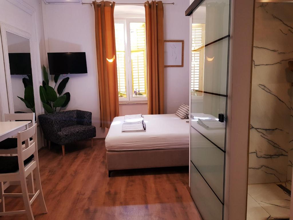 Habitación pequeña con cama, escritorio y ventana. en Room Lui en Rijeka