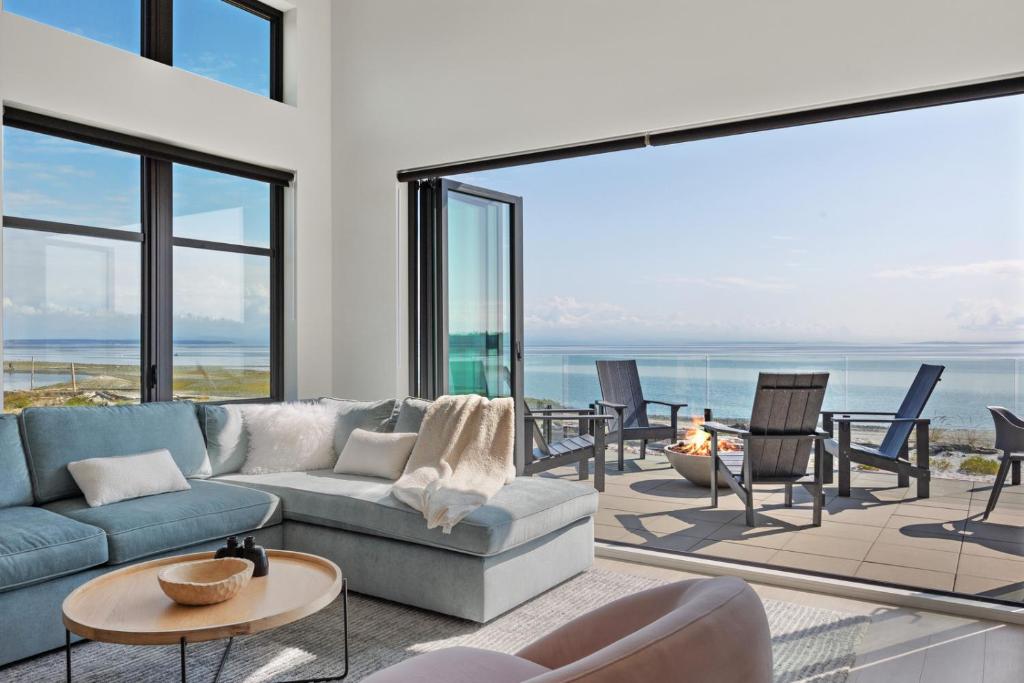 sala de estar con sofá, mesas y ventanas en Beachfront Luxury Suite #18 at THE BEACH HOUSE, en Campbell River