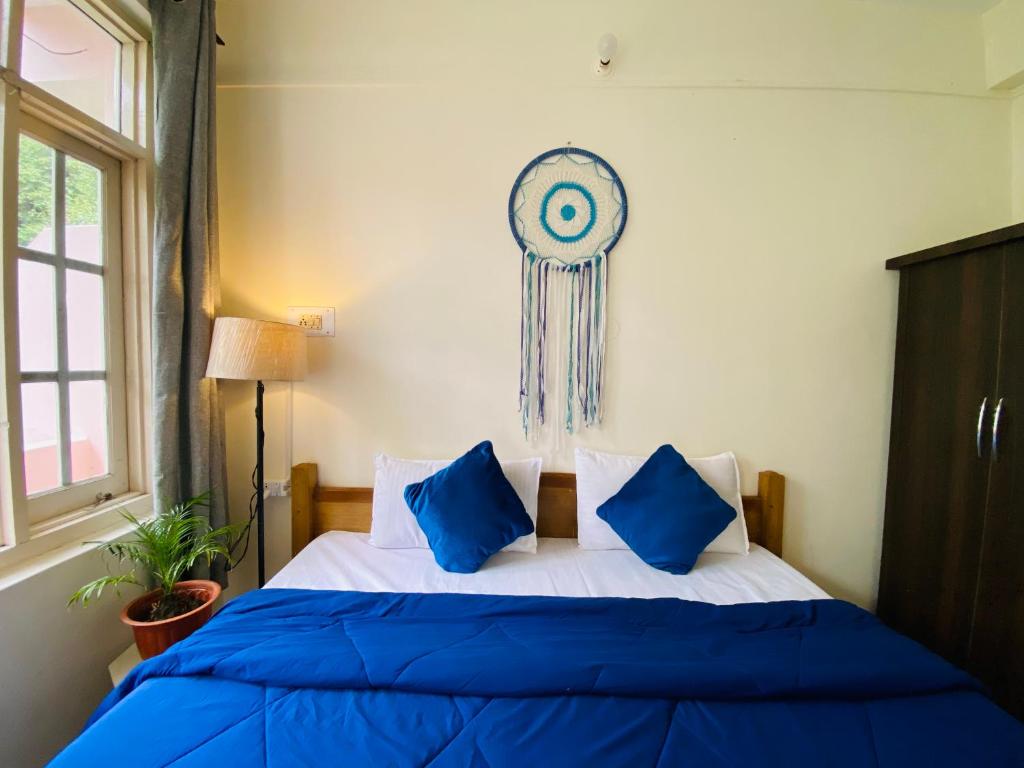ein Schlafzimmer mit einem Bett mit blauen Kissen und einer Uhr in der Unterkunft Rahgir Mcleodganj in McLeod Ganj