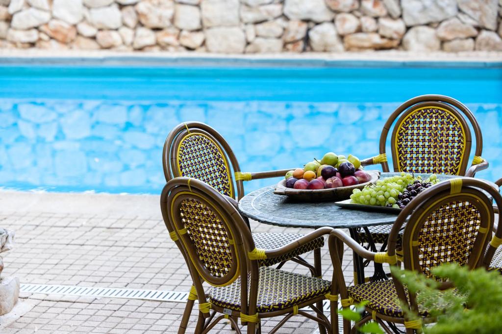 a table with a bowl of fruit on it next to a pool at THE HOUSE ROSH PINA - 2BRM WITH POOl in Rosh Pinna