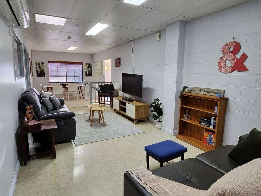 a living room with couches and a flat screen tv at Central Comfy Holiday Unit in Cooktown