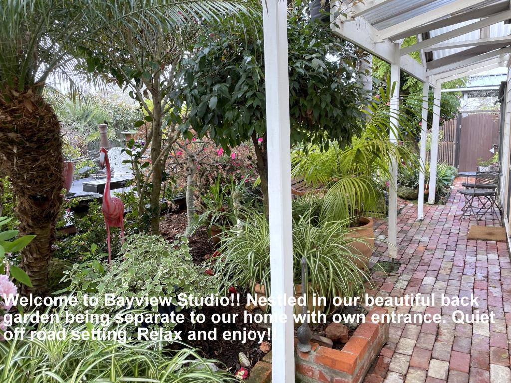 a garden with a white pergola and plants at Bayview Studio in Inverloch