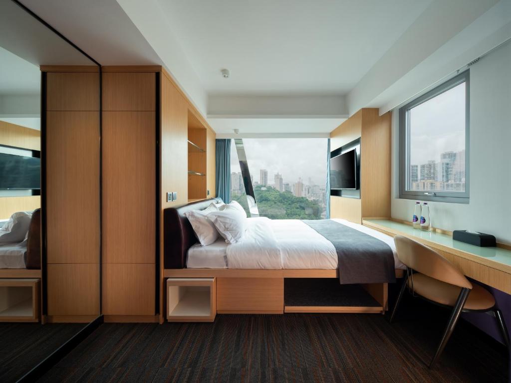 een slaapkamer met een bed, een bureau en een raam bij Greenery Inn in Macau