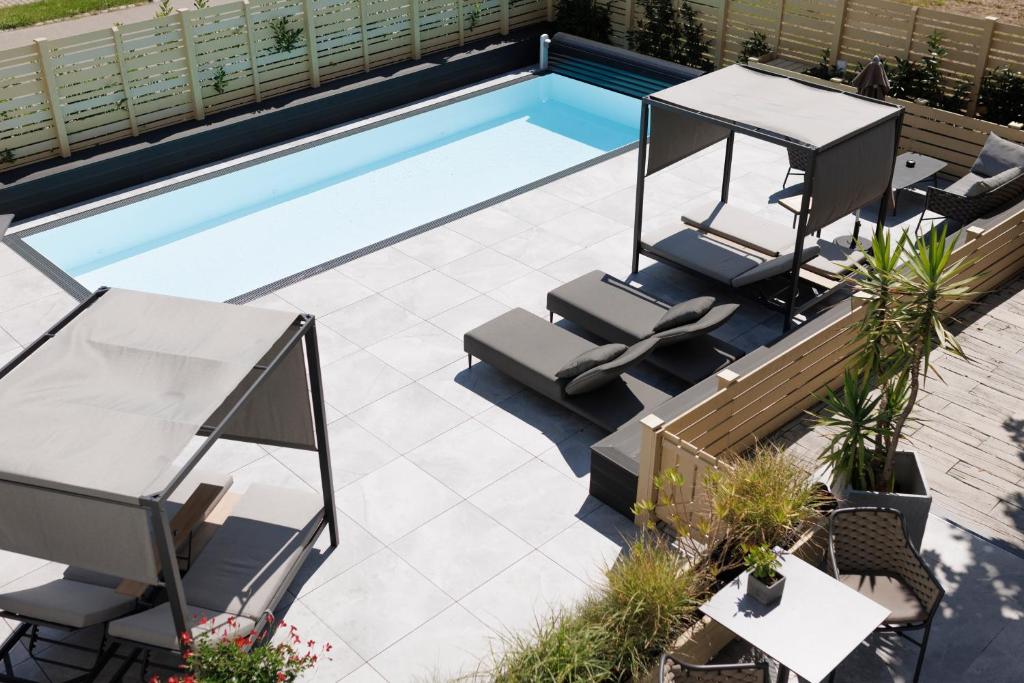 a patio with a pool and chairs and a swimming pool at Kracher Hotel Doppelzimmer in Illmitz