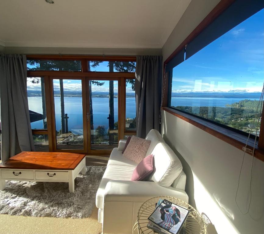 a living room with a white couch and a large window at The Nest - Relax & Unwind with Breathtaking Views over Lake Taupo in Taupo