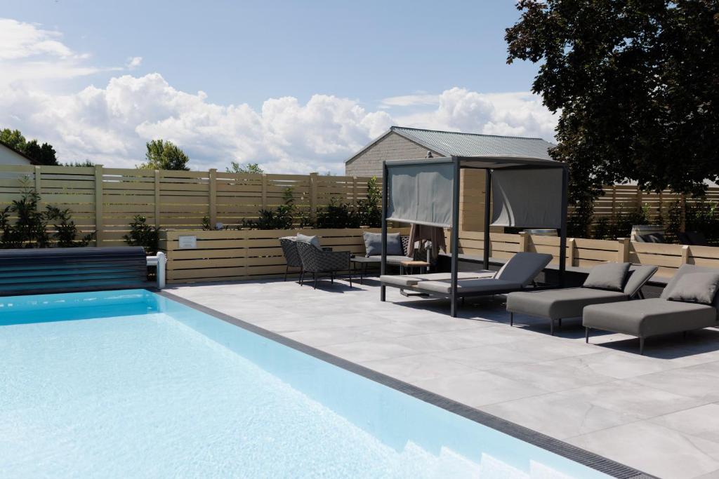 a swimming pool with chairs and a gazebo at Kracher Hotel Familienzimmer in Illmitz