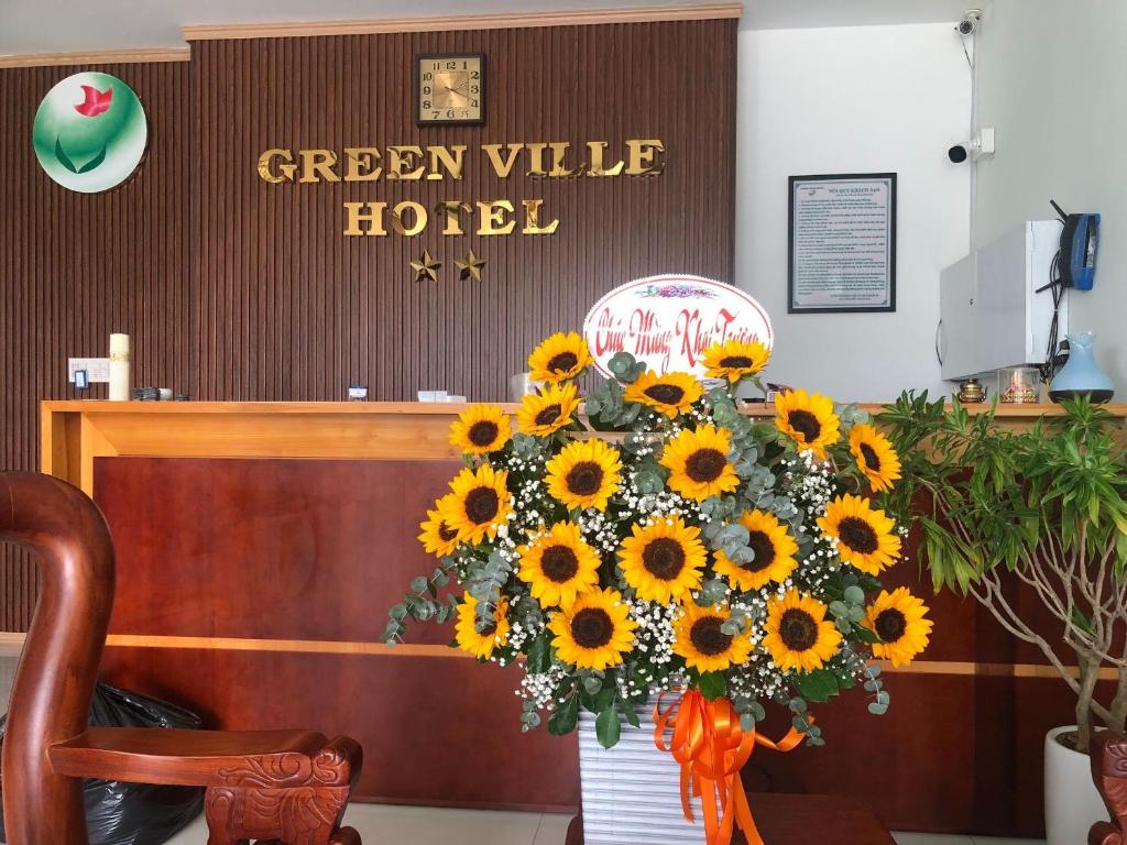 un vaso di girasoli di fronte a un verde hotel della valle di Green Ville Hotel Đồng Nai a Xa Dau Giay