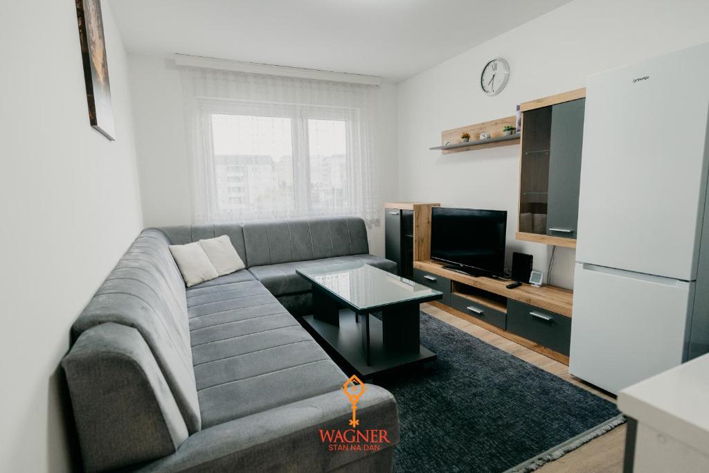 uma sala de estar com um sofá cinzento e uma televisão em Apartman Wagner em Bugojno