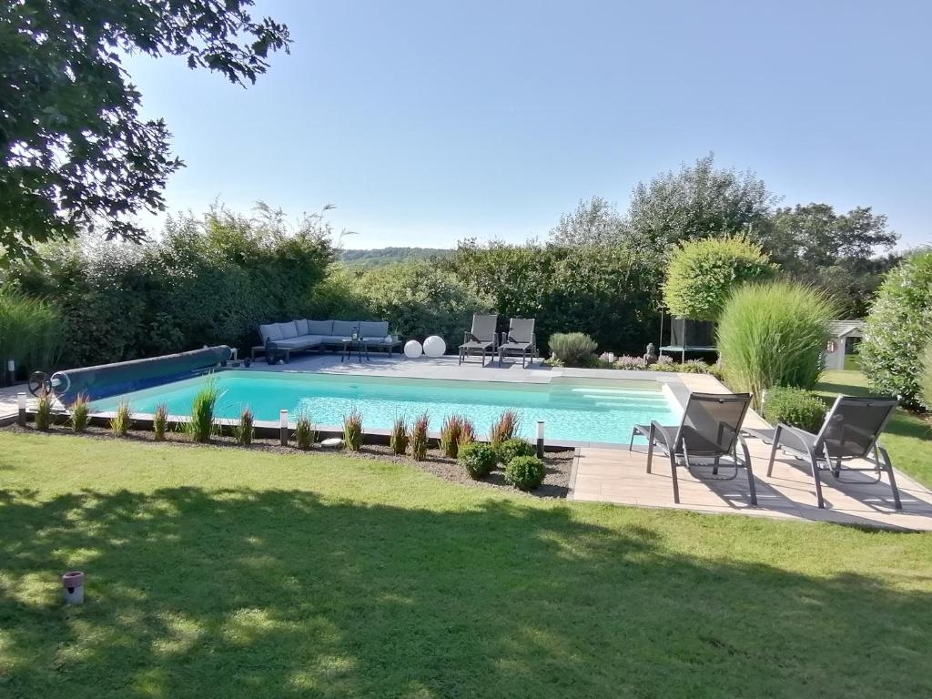 a swimming pool in a yard with chairs around it at LE CLOS DU MONTYS in Louveigné