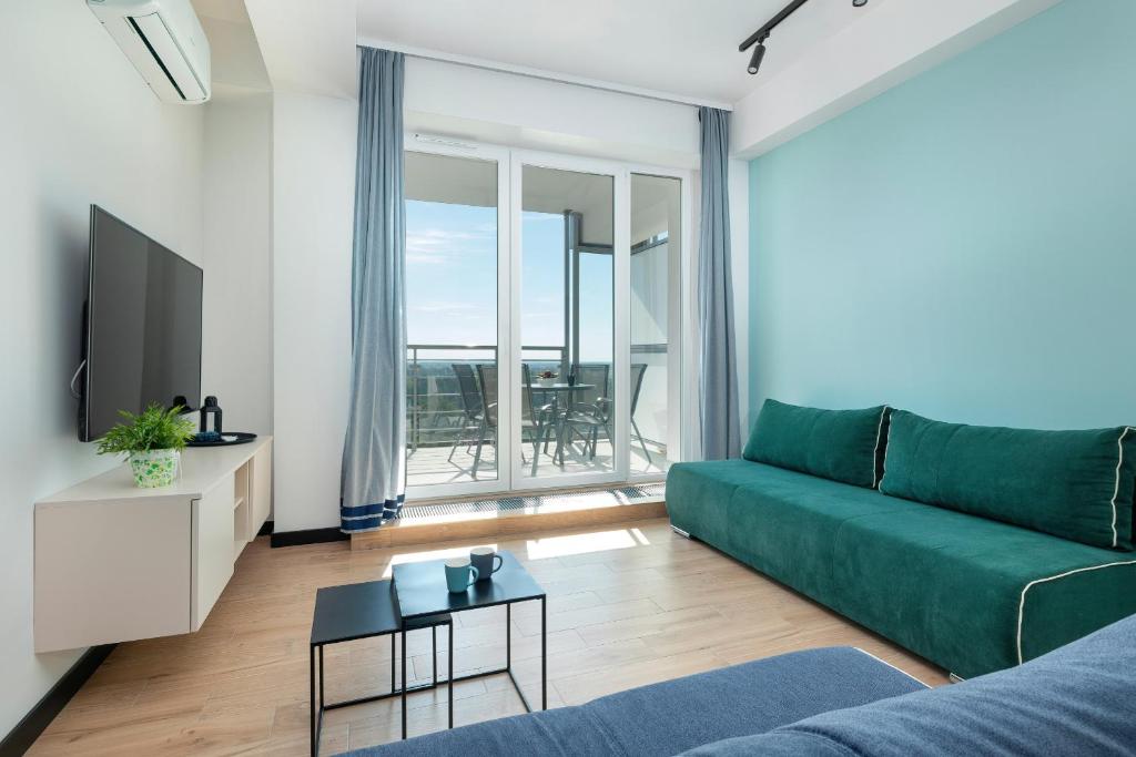 a living room with a green couch and a television at Top Water View Studio Porta Mare with AC by Renters in Dziwnówek