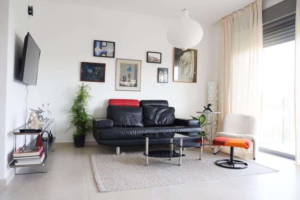 a living room with a black leather couch and chairs at Space age Jaffa Apartment in Tel Aviv