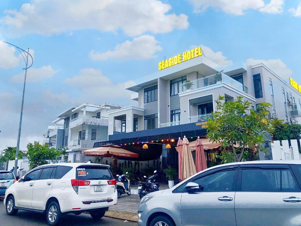 dos autos están estacionados frente a un edificio en Seaside Hotel - Rach Gia, en Rạch Giá