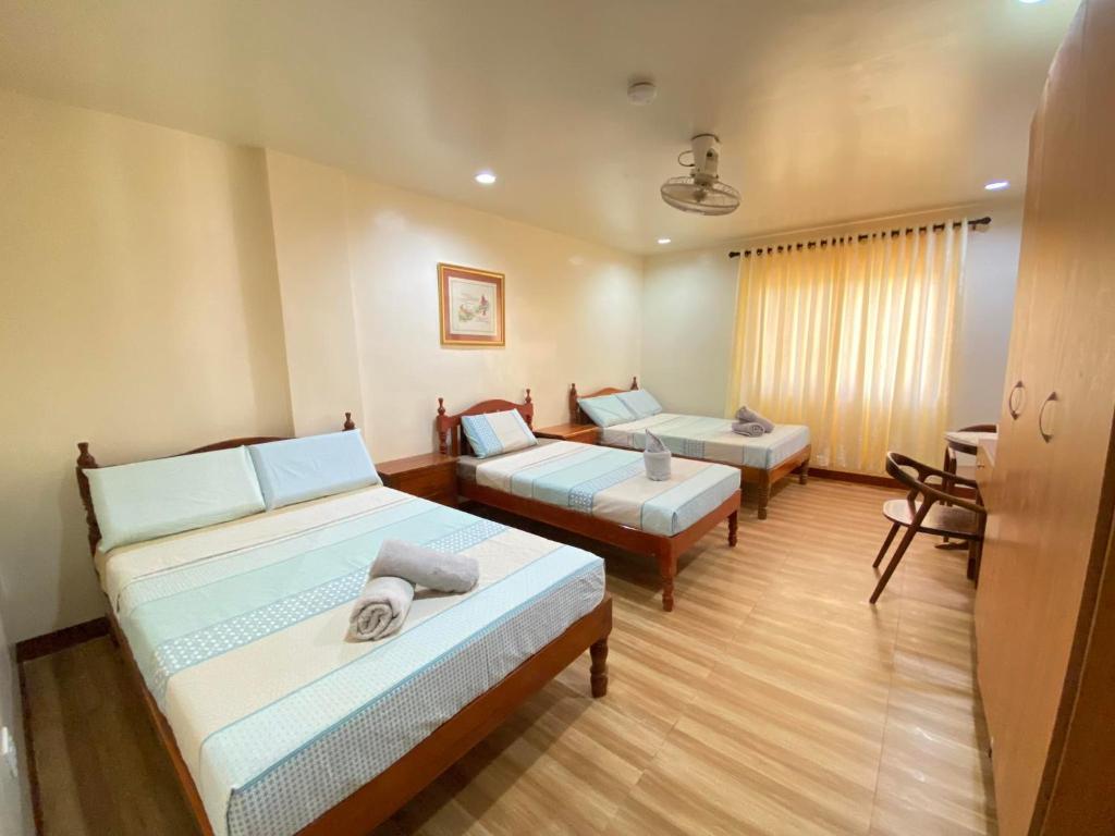 Habitación de hotel con 2 camas y escritorio en Tessie's Home Stay Bed & Breakfast en Puerto Princesa