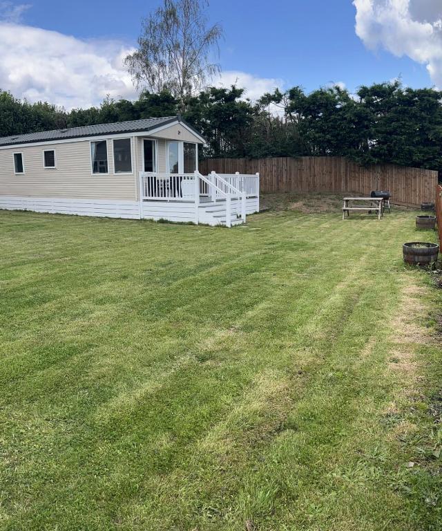 a large yard with a white house and a bench at Dedham Lodge in Lawford