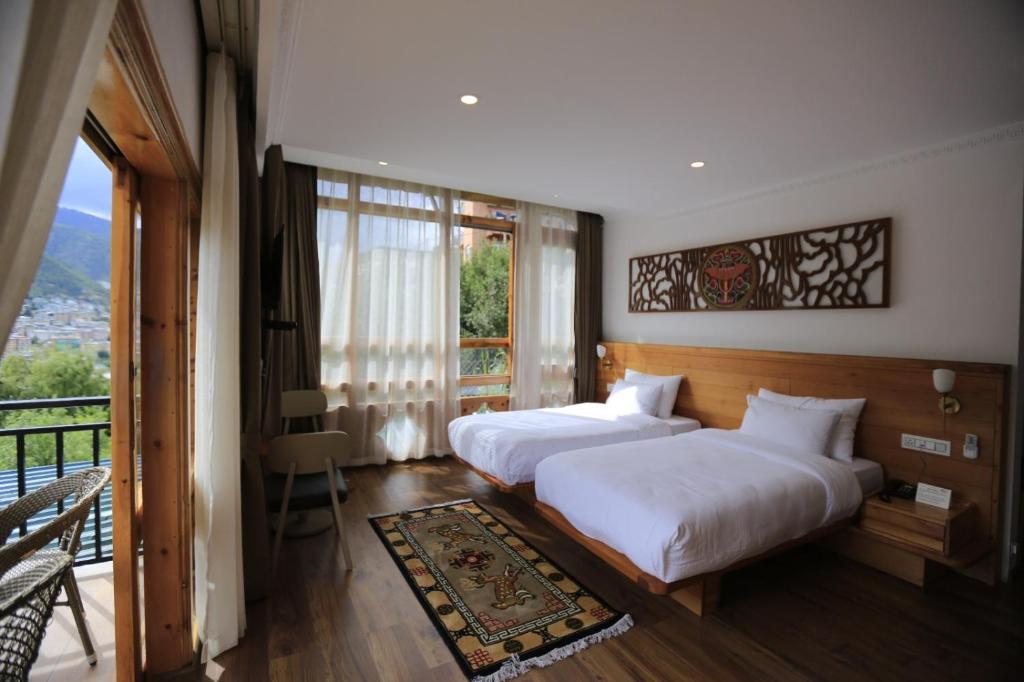 2 łóżka w pokoju hotelowym z balkonem w obiekcie Phuntsho Khangsar Hotel w mieście Thimphu
