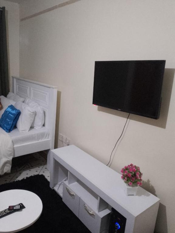 Zimmer mit einem Wand-TV und einem Bett in der Unterkunft Cool studio in south b Sanasana area in Nairobi