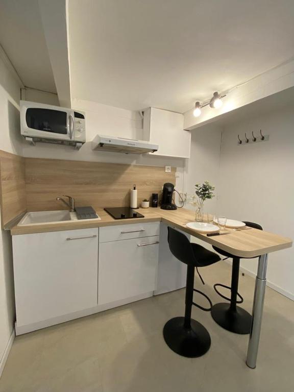 a small kitchen with a table and a microwave at Cosy Green - WIFI HD - NETFLIX GRATUIT in Avignon