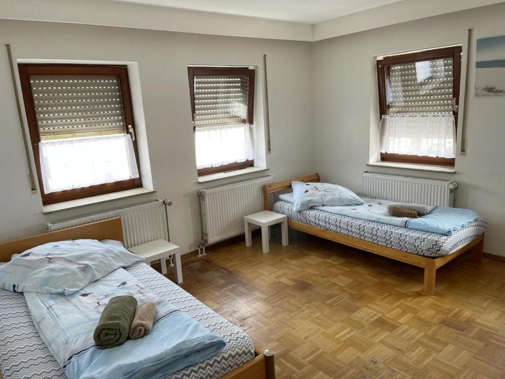 two beds in a room with two windows at Gemütliche Apartments mit Balkon in Niederstotzingen