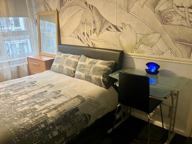 Un dormitorio con una cama y una mesa con un jarrón azul. en Private stay @ London-Stratford., en Londres
