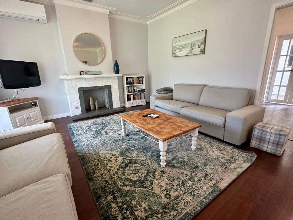 sala de estar con sofá y mesa de centro en Jacaranda Cottage, en Broadwater