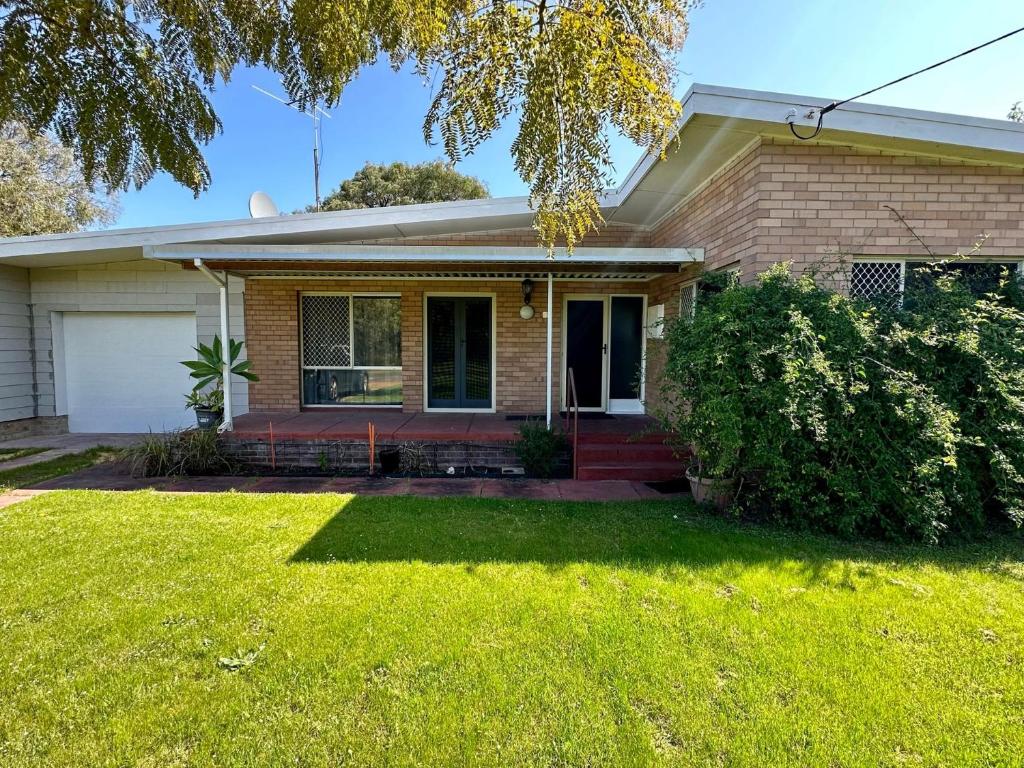 a brick house with a lawn in front of it at Jacaranda Cottage in Broadwater
