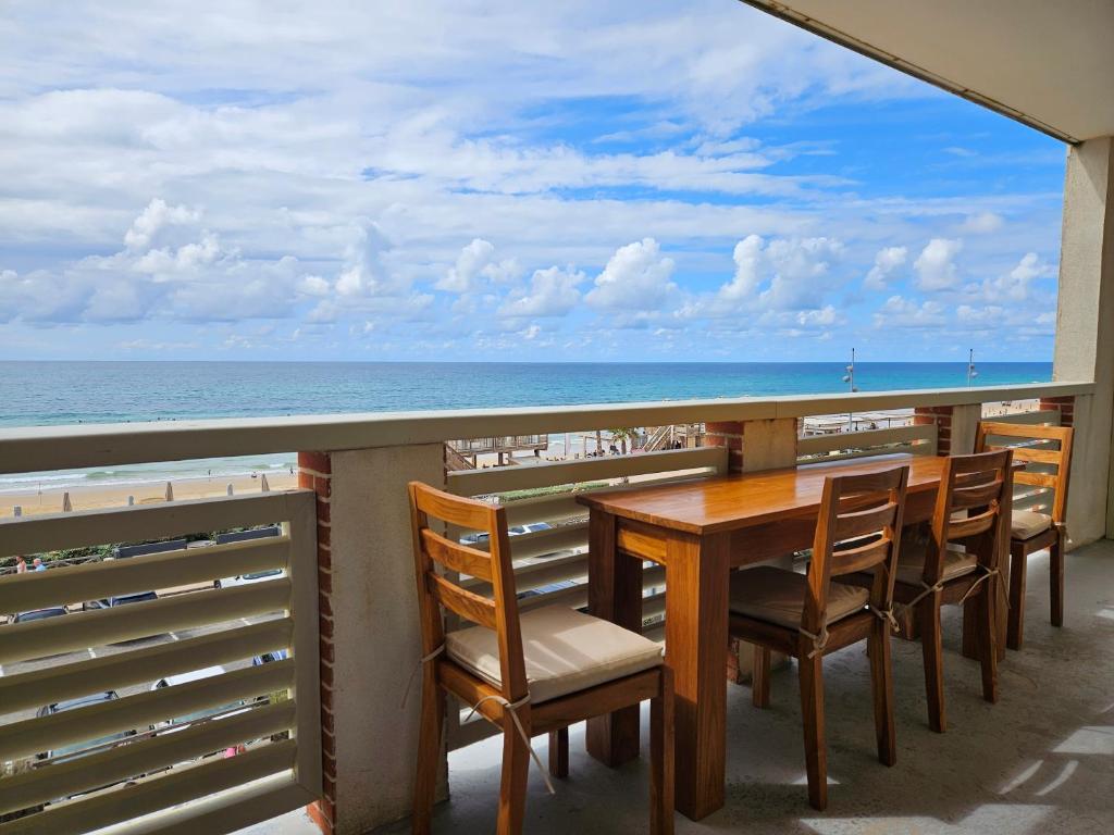 uma mesa e cadeiras numa varanda com o oceano em Résidence Pasino em Lacanau-Océan