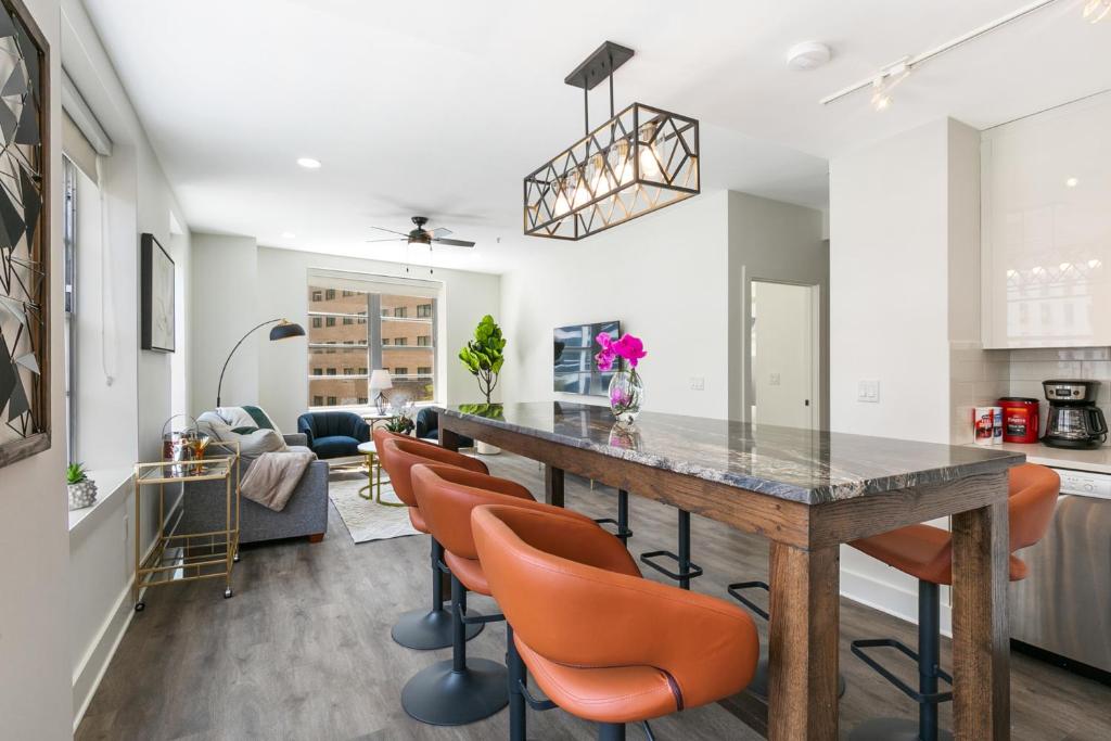 a kitchen and living room with a large wooden table and orange chairs at Chic 4BR Condo in California Building in New Orleans
