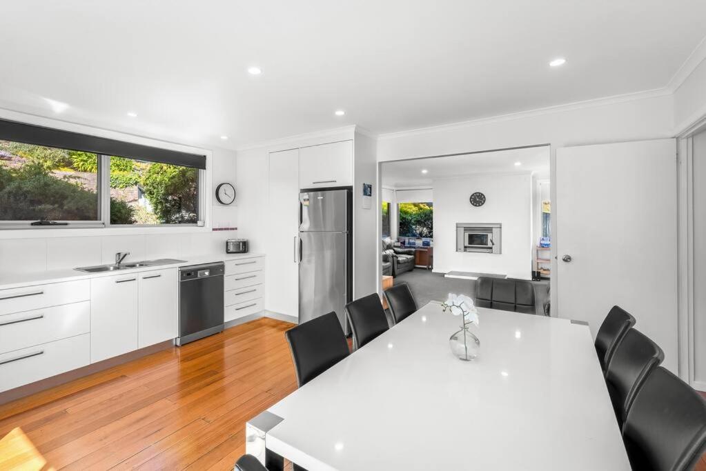 a kitchen and dining room with a white table and chairs at Large house close to the city tranquil setting in Hobart