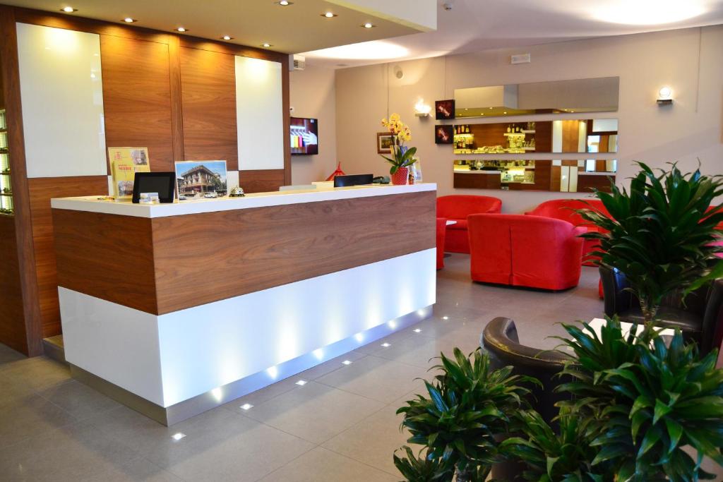 a lobby with a reception counter and red chairs at Hotel Midi in Lido di Jesolo