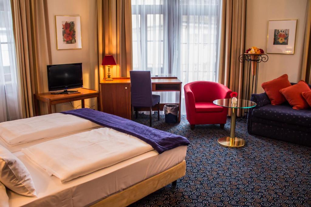 ein Hotelzimmer mit einem Bett, einem Sofa und einem Schreibtisch in der Unterkunft Stadthotel in Konstanz