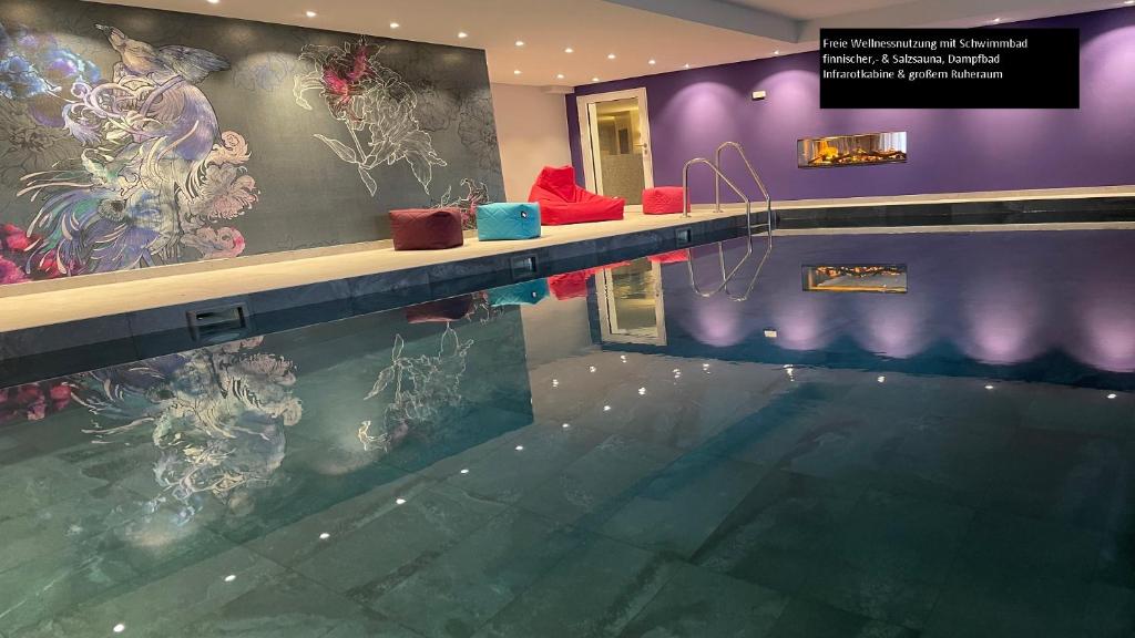 a swimming pool in a building with a painting on the wall at Parkhotel Bilm im Glück am Stadtrand Hannovers in Sehnde