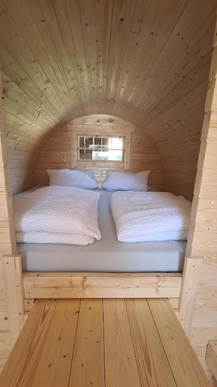 1 dormitorio con 2 camas en una cabaña de madera en Schlaffass mit Wellness in alter Scheune, en Seinsheim