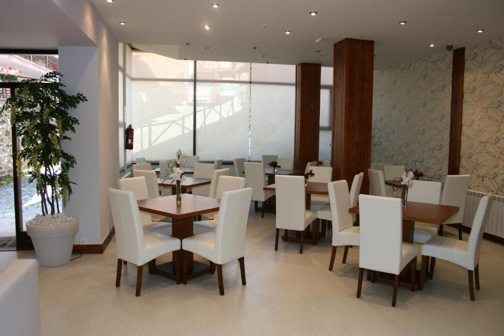 un comedor con sillas y mesas blancas en un restaurante en Hotel Arha Potes & Spa, en Potes