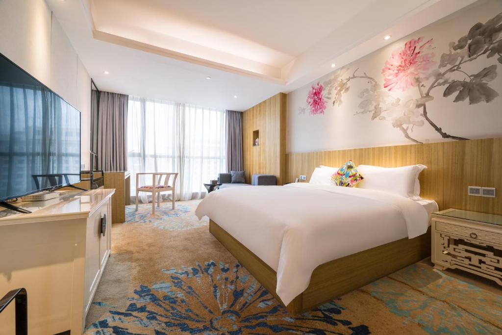 a hotel room with a large bed and a television at Paco Hotel Tаojin Metro Guangzhou-Free Shuttle Bus For Canton Fair in Guangzhou