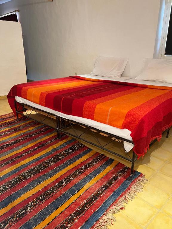 a bed with a colorful blanket on a rug at Appart-hotel la lune du desert in Erfoud