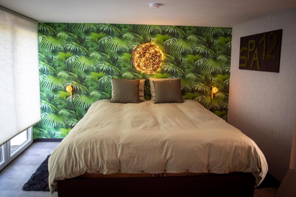 a bedroom with a large bed with a green wall at L'écurie gîte chambre in Spa