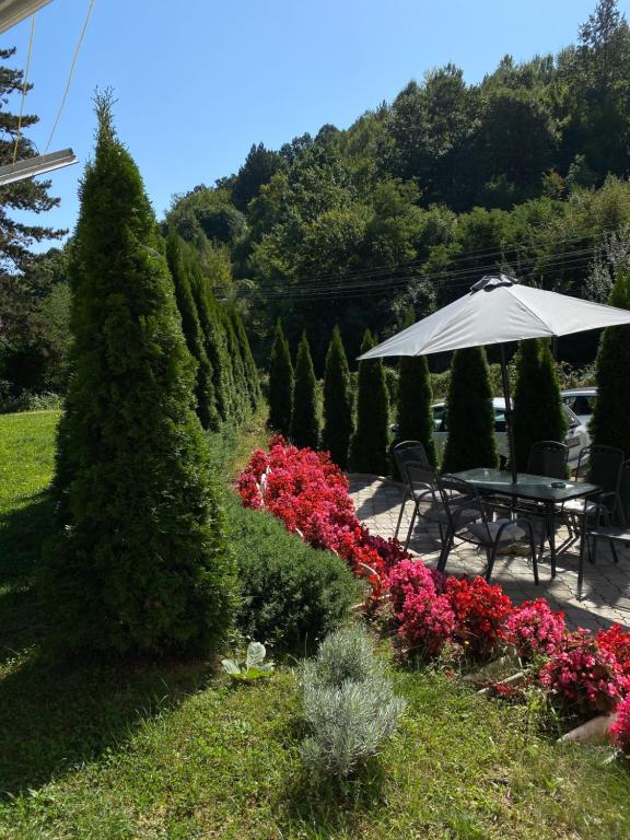 a table with an umbrella in a garden with flowers at Zeleni Dvor in Ribarska Banja