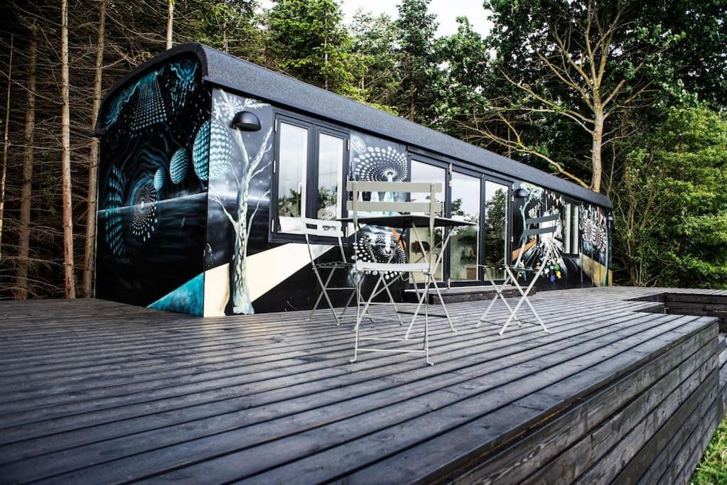 a black bus with chairs on a wooden deck at Cirkusvognen på Ærø in Marstal