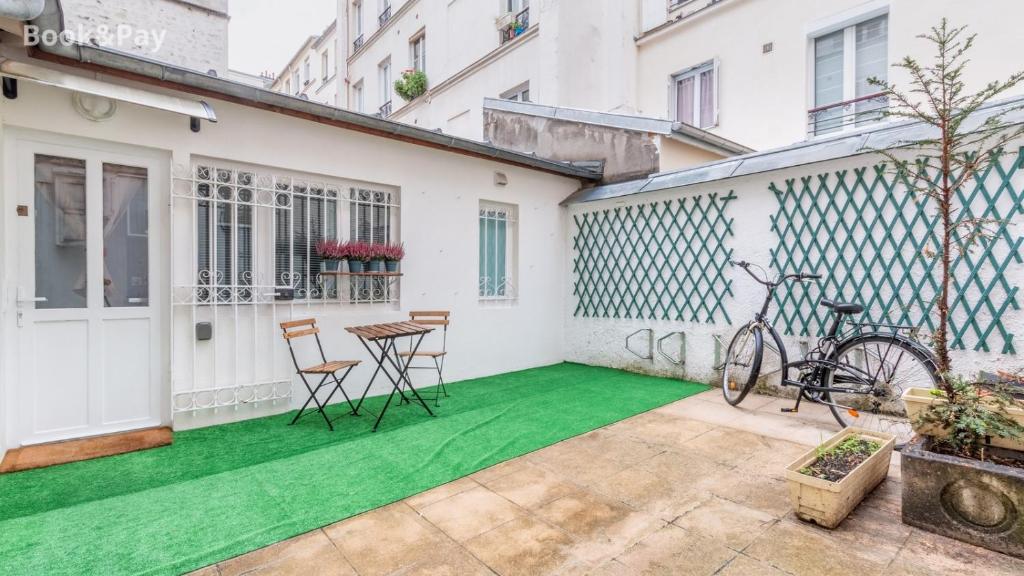 une terrasse avec un sol vert, une table et des chaises dans l'établissement Nid d'amour, à Paris