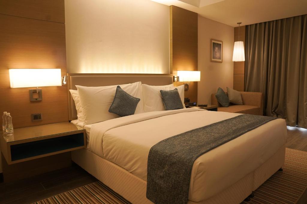 a hotel room with a large bed and a couch at Gokulam Grand Trivandrum in Trivandrum