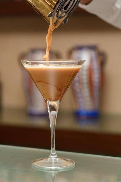 a drink being poured into a martini glass on a table at Hotel Dom Goncalo & Spa in Fátima