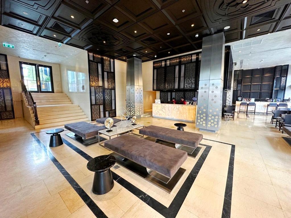 A wide lobby view showing lounge seating, reception, stairs, and a dining area.