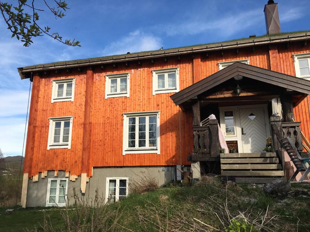 an orange house with a porch on a hill at Hyggelig lite bosted ved sjøen, nær sentrum. 