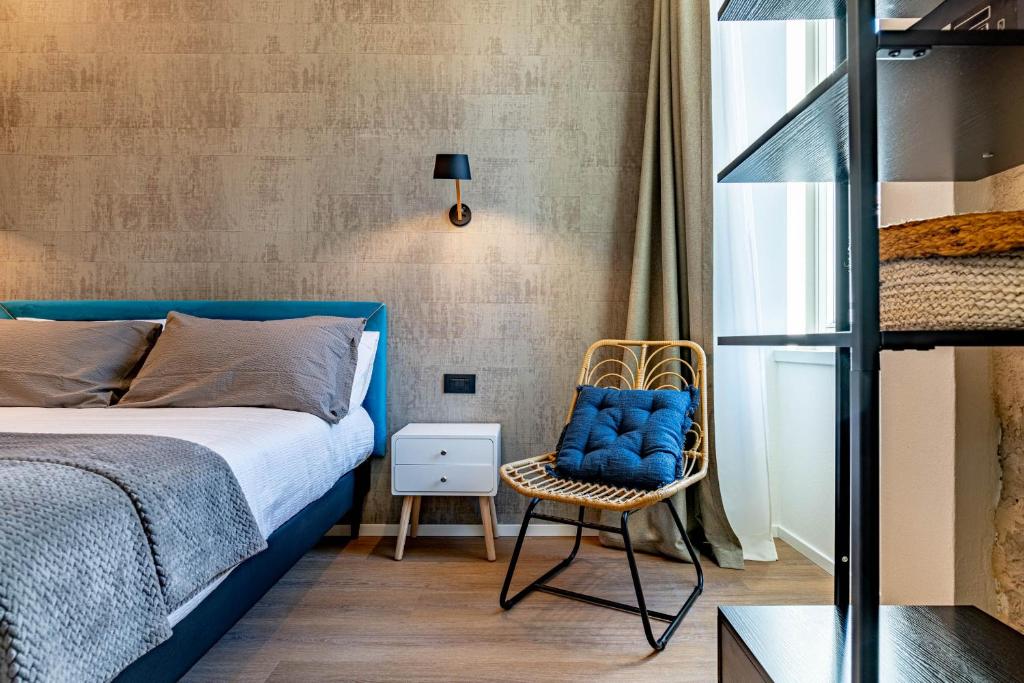 a bedroom with a blue bed and a chair at The Place - Only Self Check-in - No Reception in Trento