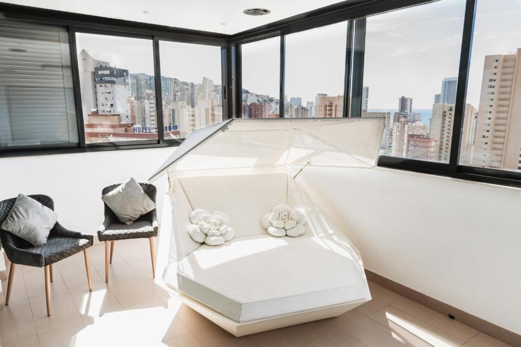 Habitación blanca con ventanas, sofá blanco y sillas en Benidorm vistas al mar, en Benidorm