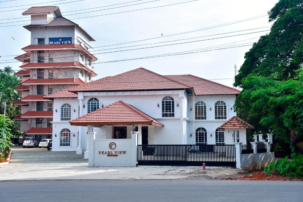 a white building with a clock tower next to a street at THE PEARL VIEW HOTEL in Mulappilangād