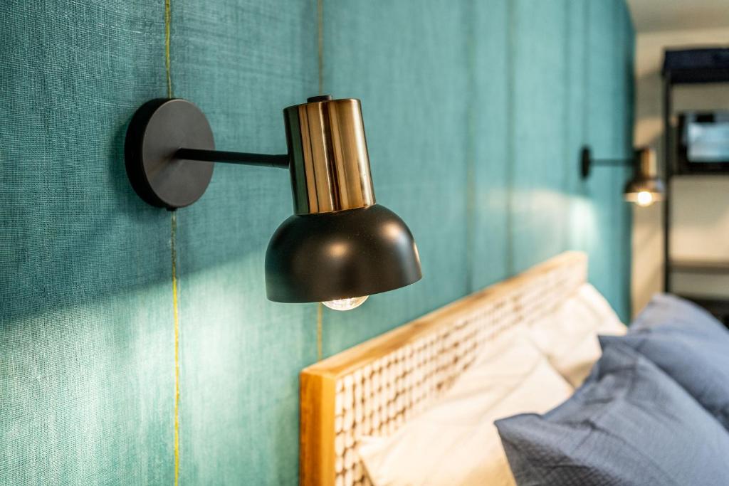 a black lamp hanging on a wall next to a bed at The Place - Only Self Check-in - No Reception in Trento