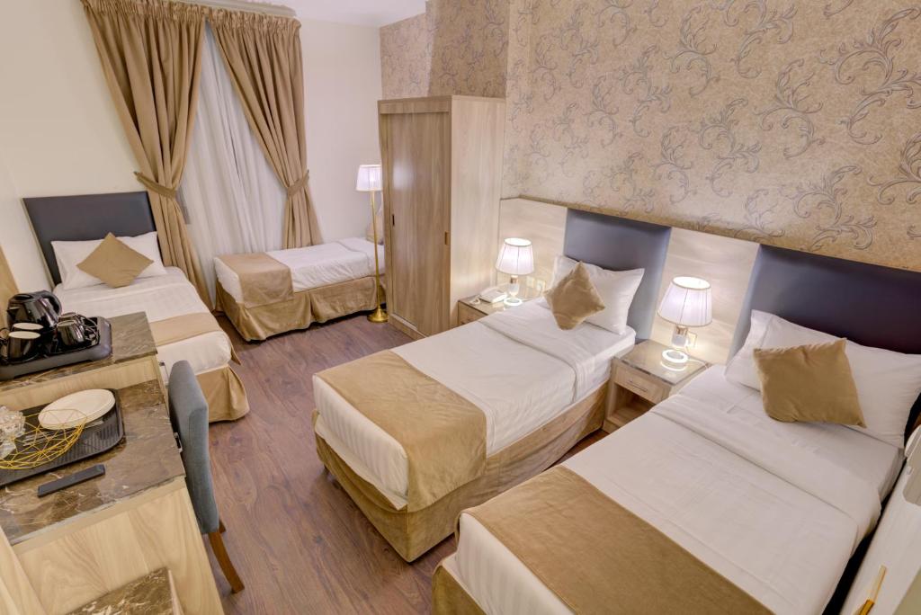 a hotel room with two beds and a table at Hayah Grand Hotel in Al Madinah